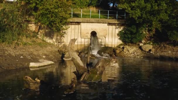 Le acque reflue del tubo fognario confluiscono nel fiume. La schiuma galleggia sulla superficie dell'acqua. L'inquinamento dell'ambiente. Il concetto di ecologia. — Video Stock