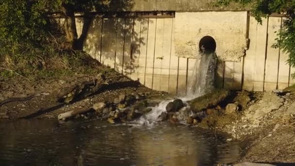 As águas residuais sujas do cano de esgoto fluem para o rio. Poluição ambiental. O conceito de ecologia. — Vídeo de Stock