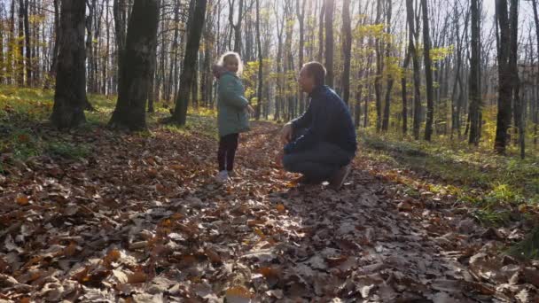 ジャケットの女の子は 再生セーターの男5人 背景には秋の森があります スローモーション 公園の父と娘 幸せな子供時代の概念 — ストック動画