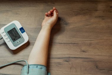 Kadın eli ve otomatik tonometre tahta masada. Cihazın ekranı çok yüksek tansiyonlu. Üst Manzara. Sağlık Konsepti
