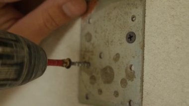 Duvara tutturulmuş metal bir vidanın vidasını söken bir tornavidayı yakından çek. Oda bitirme konsepti