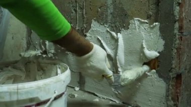 Bir alçı beton bir duvara sıva uyguluyor. Ön planda bir kova alçı var. Ön planda bir kova alçı var. Odaları bitirme kavramı