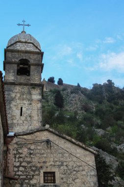 Dağların ve mavi gökyüzünün arka planına karşı Hıristiyan taş tapınağı. Karadağ 'da dini turizm kavramı