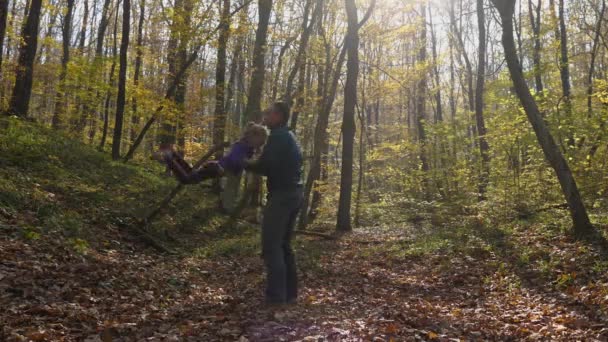 男は秋の森の中に立っている少女を投げつける 公園の父と娘 幸せな子供時代の概念 — ストック動画