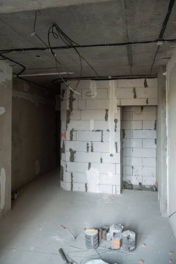 Beton tavanı, köpük duvarı ve beton zemini olan boş bir oda. Tavandan sarkan elektrik kabloları var. Oda yenileme konsepti