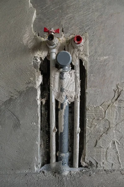 There are three plastic pipes in the concrete wall. Two for cold and hot water. The third for sewage. One pipe with a faucet, the others with plugs. The concept of repair of the premises