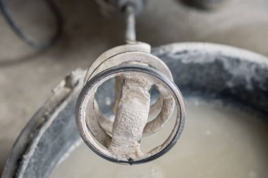 Bir kova suyun üzerine kuru karışımları karıştırdığı için yumruk makinesindeki kirli hortum. Seçici Odaklanma. Tamir ve onarım konsepti