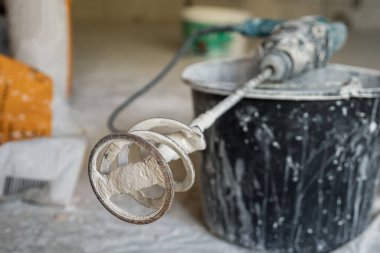 Siyah plastik kovanın üzerinde kuru karışımları karıştırmak için eklenmiş bir zımba aleti var. Seçici odaklanma. Tamir için profesyonel elektrikli aletler. Binanın onarımı ve bitmesi