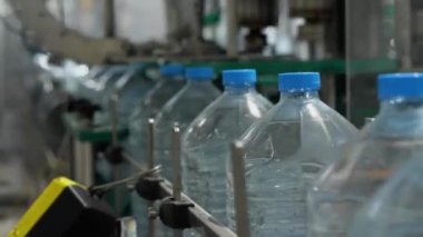 Beş litrelik şişeler konveyör boyunca hareket ediyor. Su üretim hattı. Mineral Su Üretim Tesisi