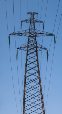 Mavi gökyüzü arka planına karşı yüksek voltajlı elektrik direğinin uzun metal yapısı. Panoramik fotoğraf