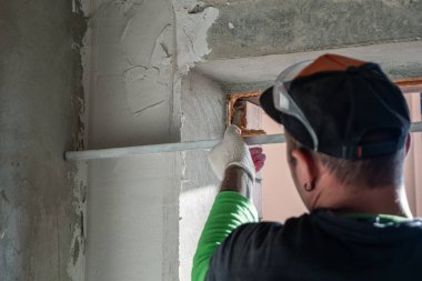 Alçılı bir duvar alüminyum bir kuralla yerle bir ediliyor. Oda bitirme konsepti