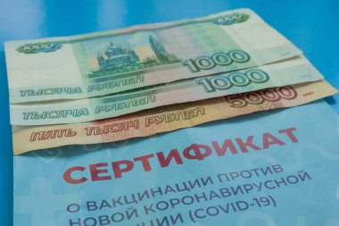 Mavi arka planda 7000 ruble ve Covid-19 'a karşı aşı sertifikası var. Yakın plan. Çeviri: yeni bir koronavirüs enfeksiyonuna karşı aşı sertifikası COVID-19
