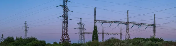 Yüksek Voltajlı Elektrik Kuleleri Yeşil Çimenlikteki Kablolarla Mor Mavi Gökyüzünün — Stok fotoğraf