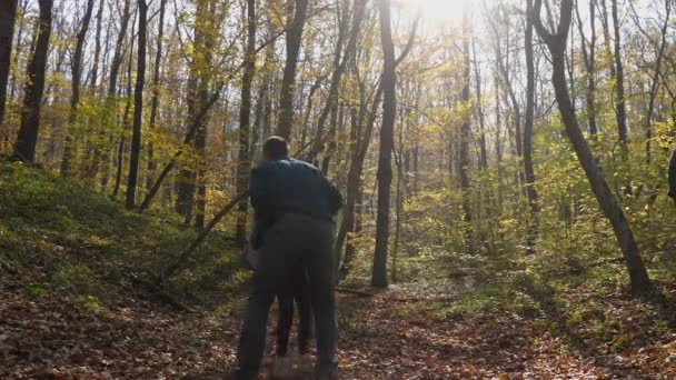 Hombre Lanza Una Niña Pie Bosque Otoño Vista Desde Atrás — Vídeos de Stock