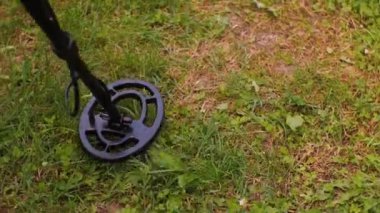 Kamera metal dedektörünün hareketlerini takip ediyor. Ağır çekim. Eski paraları bulma kavramı