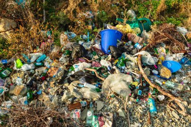 Doğayı doldurun. Plastik, cam, kağıt ve alüminyum çöpler, kayalar ve çimenler arasında. Çevreyi koruma kavramı. Rusya, Krasnodar Bölgesi, 26 Ekim 2021