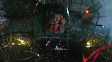 Mutlu yıllar 2022. Kamera Noel ağacının tepesinden koniler, çelenkler ve simlerle temeline doğru hareket ediyor. Tahta Noel ağacı, kar tanesi, şampanya mantarları ve 2022 rakamları.