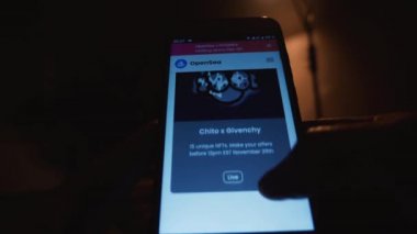Karanlık bir odada akıllı telefon ekranında NFT koleksiyonunu karıştıran bir adam. OpenSea platformundaki dijital sanat eserlerine bakıyorum. Yakın plan. Rusya, Krasnodar Bölgesi, 25 Kasım 2021