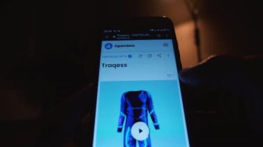 Karanlık bir odada parmağı akıllı telefonunda olan bir adam bir NFT jetonu seçiyor ve hemen satın alıyor. OpenSea web sitesinden dijital sanat eserlerine göz atın ve satın alın. Rusya, Krasnodar Bölgesi, 25 Kasım 2021