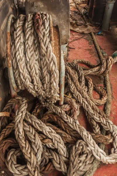 Dirty ship\'s rope uncoiled lying among the debris on board the shipwrecked ship. View from the ship