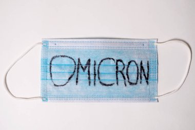 Beyaz arka planda Omicron harfleri yazılı mavi tıbbi maske. Yeni bir tür Coronavirus covid 19 'a karşı koruma.