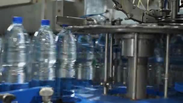 Il funzionamento della tappatrice di plastica. La fotocamera si muove da sinistra a destra. Impianto per la produzione di acqua minerale e bevande analcoliche. — Video Stock