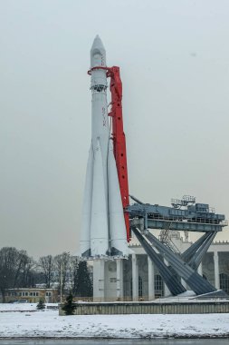 Dünyalar ilk olarak Vostok 'u Moskova' daki bir sergide üç aşamalı uzay roketi ile donattılar. Arka plan gri gökyüzü ve kar taneleri..
