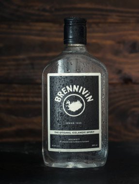 Brennivin 'in buzlu şişesi yakın zamanda dondurucudan çıkarıldı. Koyu ahşap arka planda su damlaları var. Geleneksel İzlanda ruhları. Rusya, Krasnodar, 6 Aralık 2021