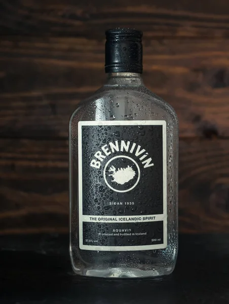 Brennivin 'in buzlu şişesi yakın zamanda dondurucudan çıkarıldı. Koyu ahşap arka planda su damlaları var. Geleneksel İzlanda ruhları. Rusya, Krasnodar, 6 Aralık 2021