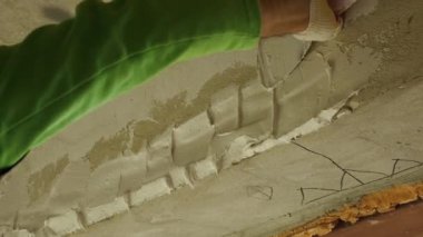 Küçük bir malayla duvara alçı yapıştıran bir adamın yakın çekimi. Oda bitirme konsepti