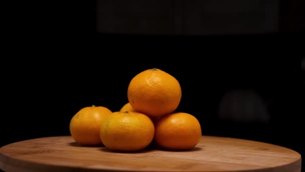 Gula mogna tangeriner på en träbakgrund. Kameran flyger runt. Parallellaxeffekt. — Stockvideo