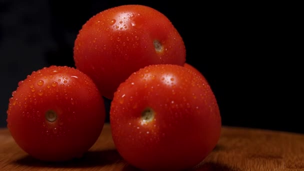 在一块木板上放着一束成熟的红色西红柿 上面有凝结的水滴 黑色背景 摄像机在周围飞来飞去 视差效应 — 图库视频影像