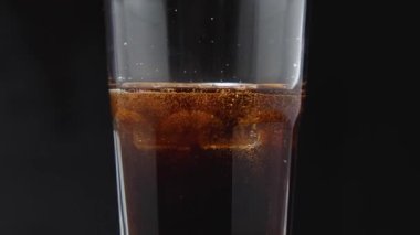 Buzlu bir bardak ve mutfak tahtasının üzerinde karbonatlı bir içecek. Kamera etrafta uçuyor. Parallaks etkisi. Koyu arkaplan.