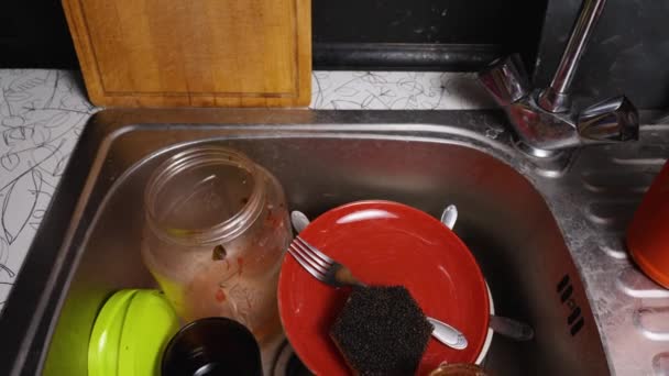 Smutsiga tallrikar, burkar, muggar och bestick i metallvasken. Kamerarörelse uppifrån och ner. Närbild. — Stockvideo