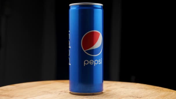 Pepsi in een 250 ml aluminium blik op een keukenbord, op een zwarte achtergrond. De camera vliegt rond. Parallax-effect. — Stockvideo