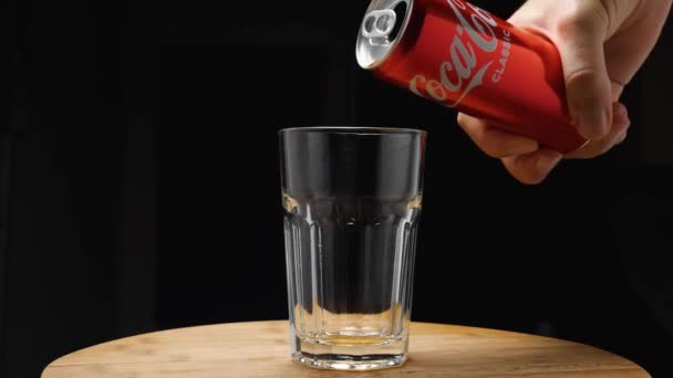 Une main d'homme d'une boîte verse du Coca-Cola dans un verre à boule haute. La caméra vole. Effet parallaxe. Fond sombre. — Video