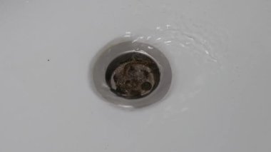 Gevşek saçlar yüzünden tıkanmış banyo gideri. Bir tutam saç gideri tıkıyor. Yakın plan..