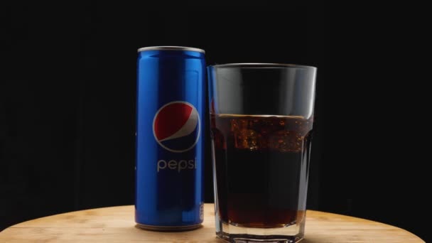 Highball glass with Pepsi and ice, next to an aluminum Pepsi can on a black background. The camera flies around. Parallax effect. — Vídeo de Stock