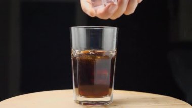 Bir adamın elindeki ağır çekim görüntüleri, bir bardak karbonatlı içeceğe buz fırlatıyor. Kamera etrafta uçuyor. Parallaks etkisi