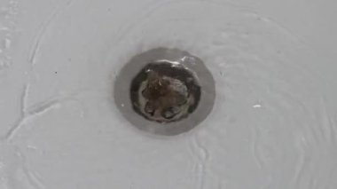 Bir tutam gevşek saç gideri engelliyor. Saç küvet giderini tıkamış. Yakın plan.