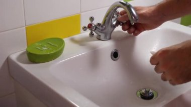 Bir adam lavaboda akan suyun altında ellerini sabun ve suyla yıkar. Yakın plan. Hijyen ve koronavirüsün önlenmesi kavramı