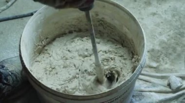Bir kovada macunu karıştırırken yakın plan. Odayı bitirme konsepti. Rusya, Krasnodar, 20 Ekim 2021
