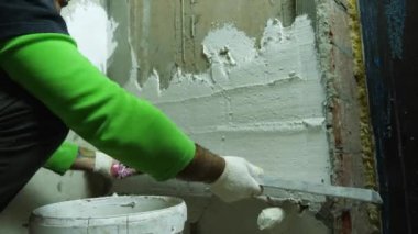 Tamirci beton duvardaki alüminyum cetvelle alçıyı düzleştiriyor. Ön planda bir kova alçı var. Odaları bitirme konsepti. Rusya, Krasnodar, 20 Ekim 2021