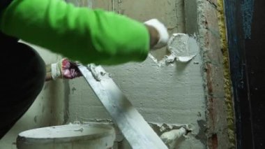 Tamirci beton bir duvara alçı uyguluyor. Ön planda bir kova alçı var. Odaları bitirme konsepti. Rusya, Krasnodar, 20 Ekim 2021