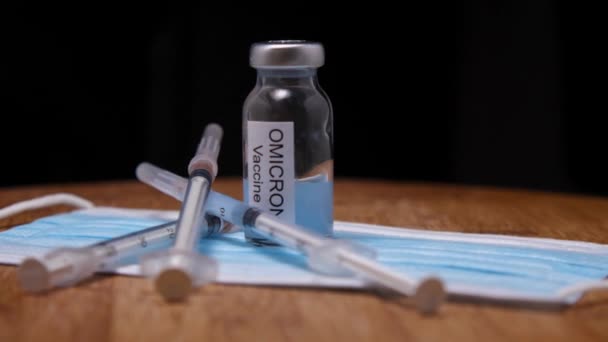 医疗面罩 注射器和木制背景的Omicron疫苗瓶 摄像机在周围飞来飞去 视差效应 欧米克隆是Covid 19的一种新物种 — 图库视频影像