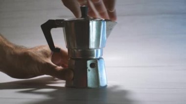 Bir adamın elleri kahve yapmak için gayzer kahve makinesini söker. Hafif arkaplan. Evde lezzetli kahve yapma süreci.