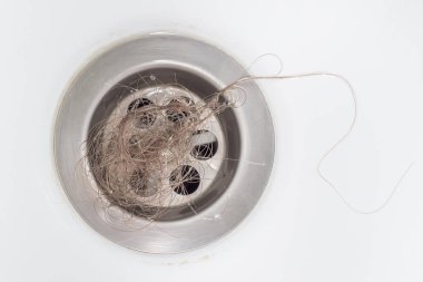 A bundle of blonde women's hair was left in the bathroom drain after taking a shower. Close-up, top view. The problem of hair loss