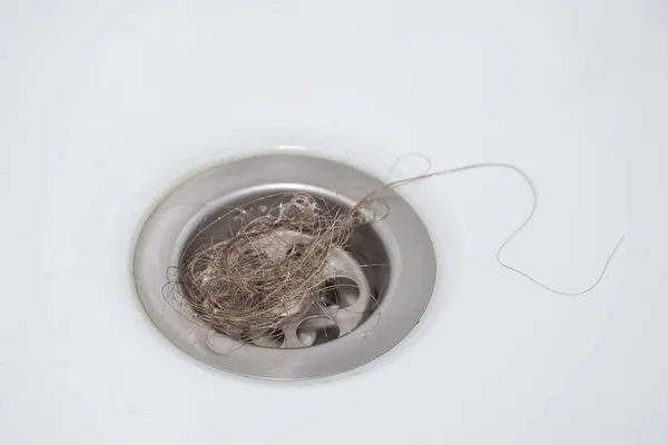 A bundle of women\'s loose hair was left in the bathroom drain after taking a shower. The problem of hair loss