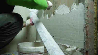 The repairman is plastering a concrete wall. In the foreground there is a bucket of plaster. The concept of finishing the rooms. Russia, Krasnodar, October 20, 2021
