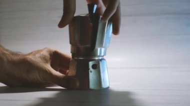 Man's hands assemble a geyser coffeemaker ready to make coffee. Light background. The process of making delicious coffee at home